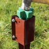Close up of a post support driving tool being hit with a mallet to knock a post support into the ground