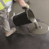 Self levelling compound being poured onto the floor out of a bucket
